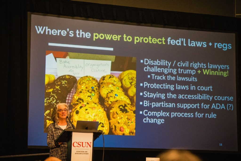 Lainey stands at the CSUN lecturn with her big picture of cookies in the presentation, next to some bullets about the federal laws and regulations.